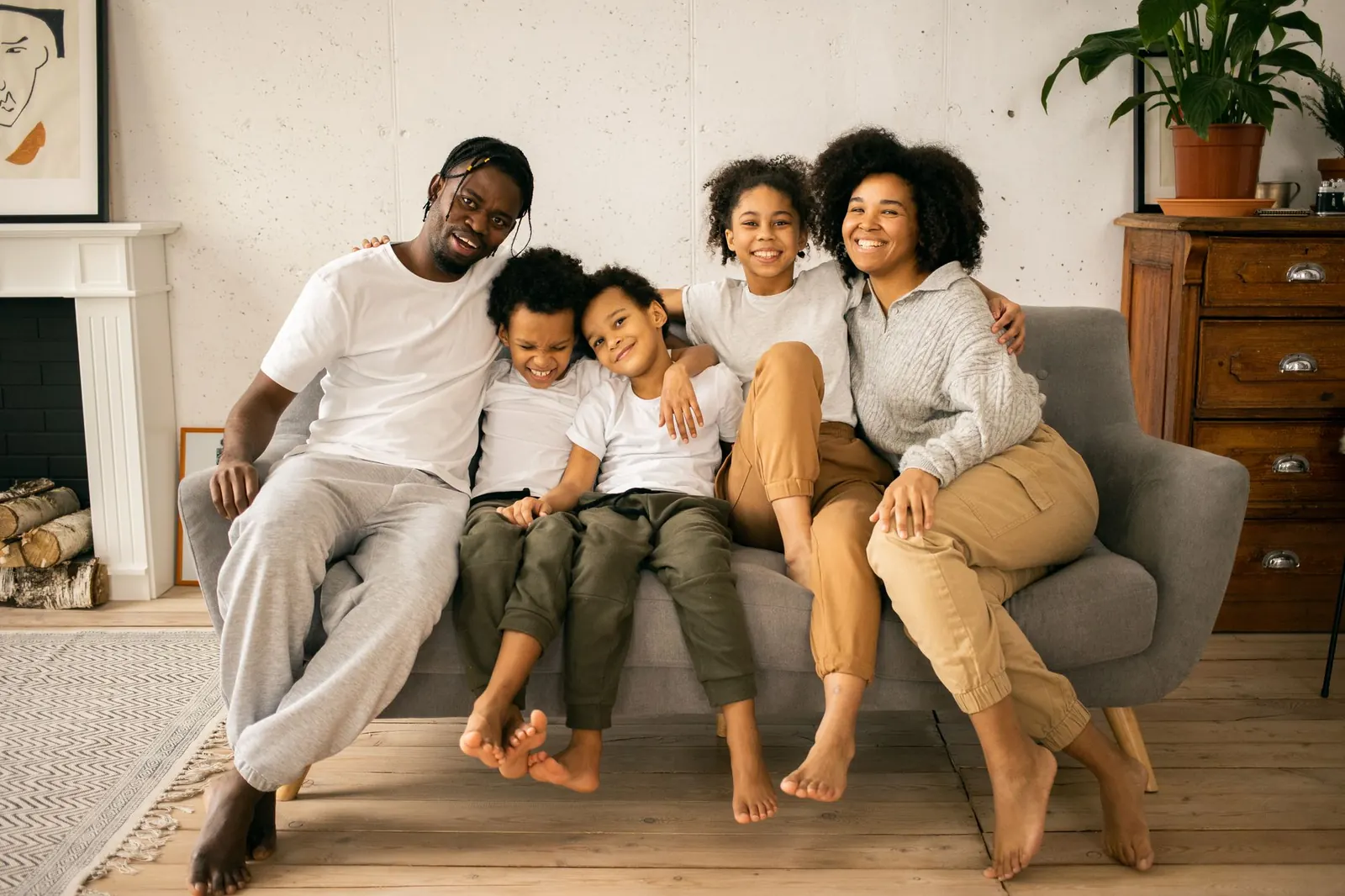 A family of five sitting together on a sofa at home