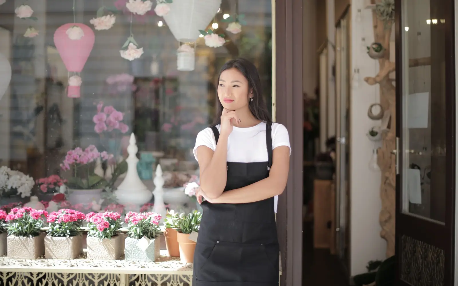 The owner of a small flower shop standing in the doorway of her store