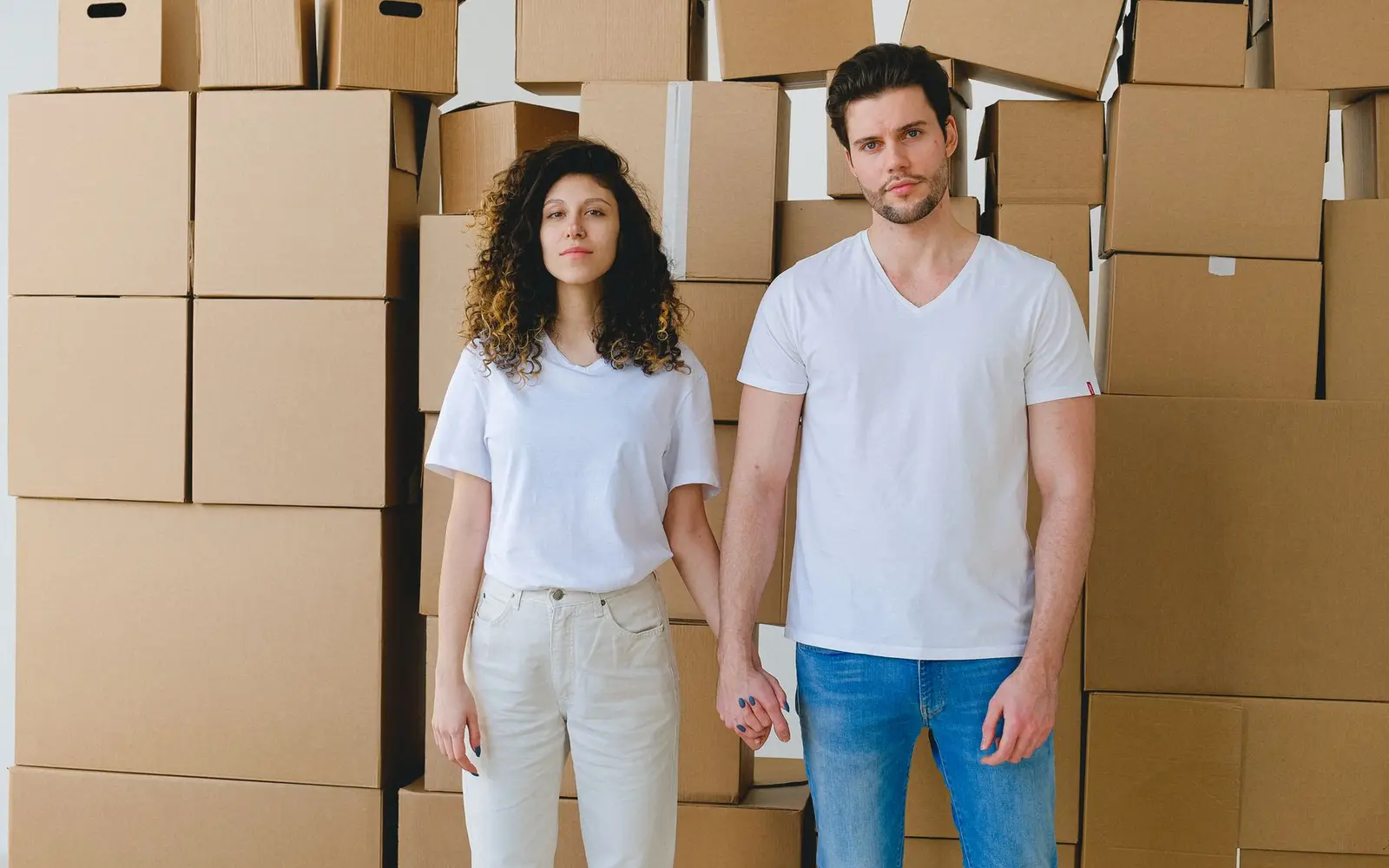 A couple standing among stacked moving boxes in a newly bought home