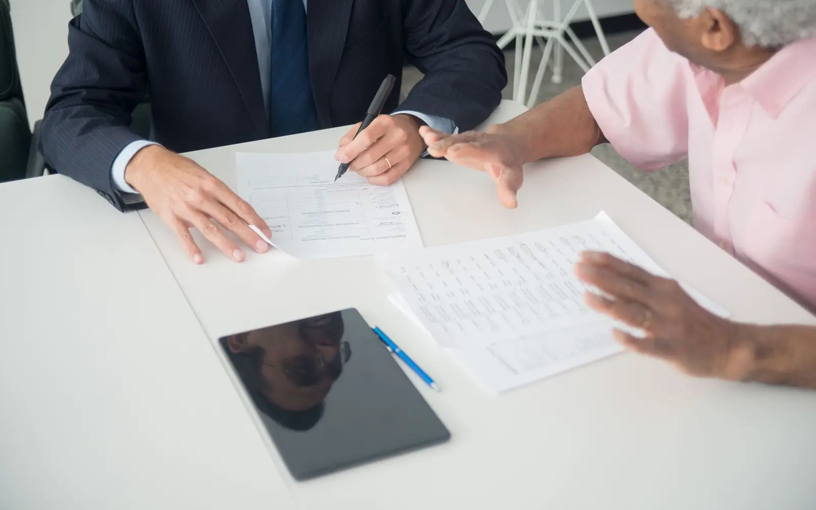 An agent and a client working through an application form across a desk