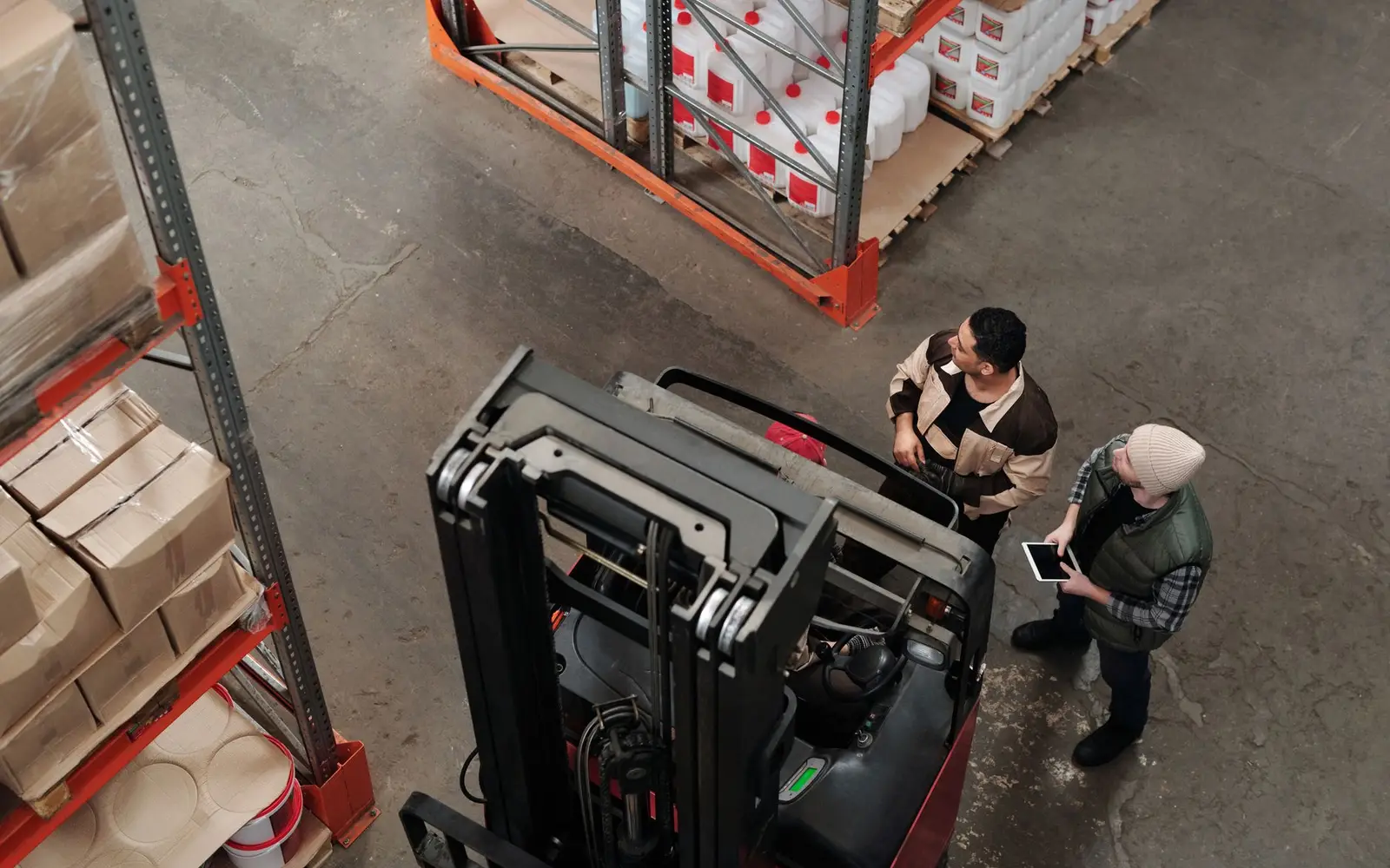 Warehouse staff moving stock beside a forklift in a small distribution unit